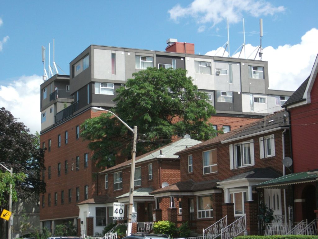 two storey houses line the sidewalk leading to 25 leonard building, a 40 kmh sign is in the foreground